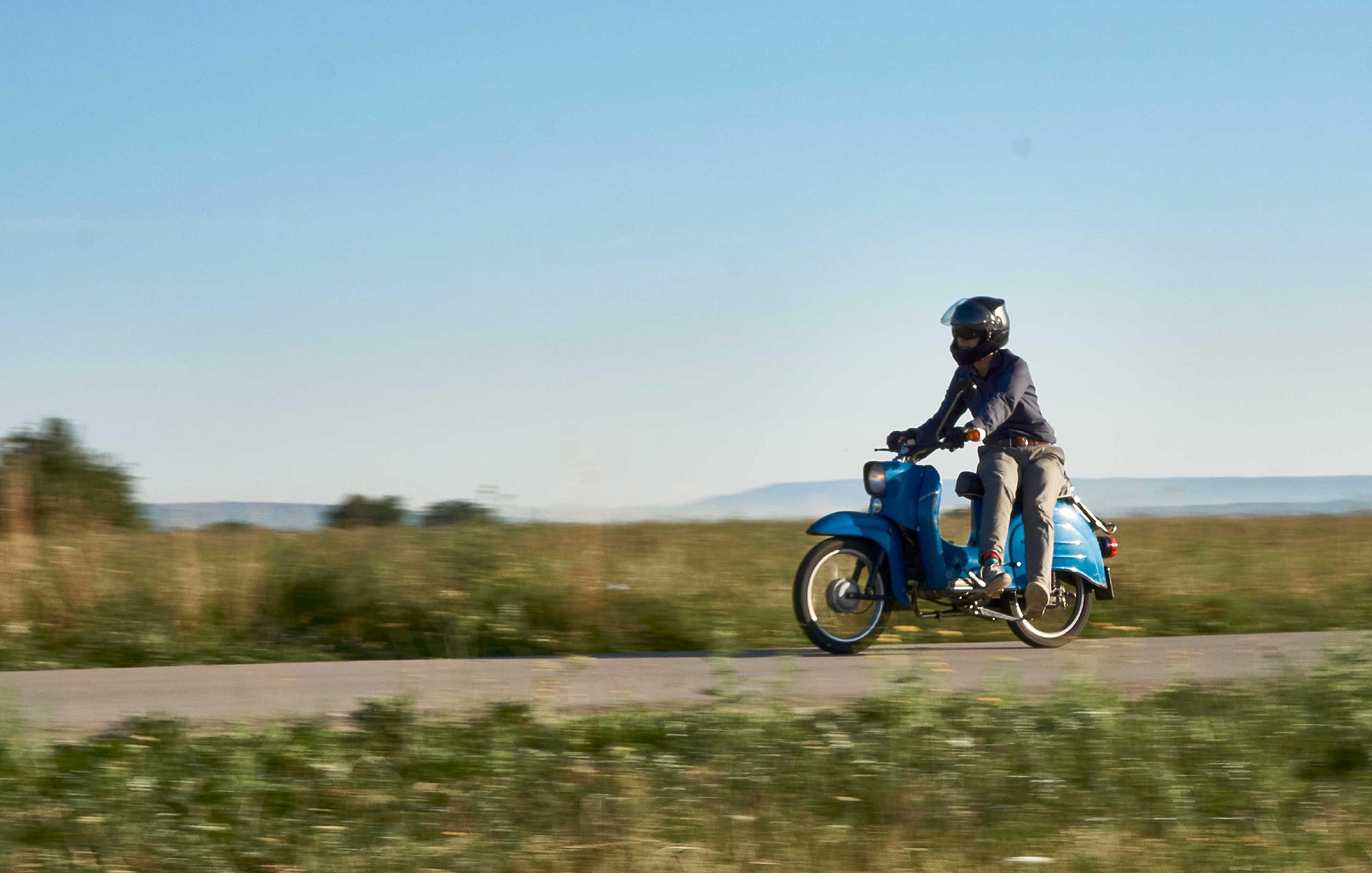 Person riding a blue motor scooter