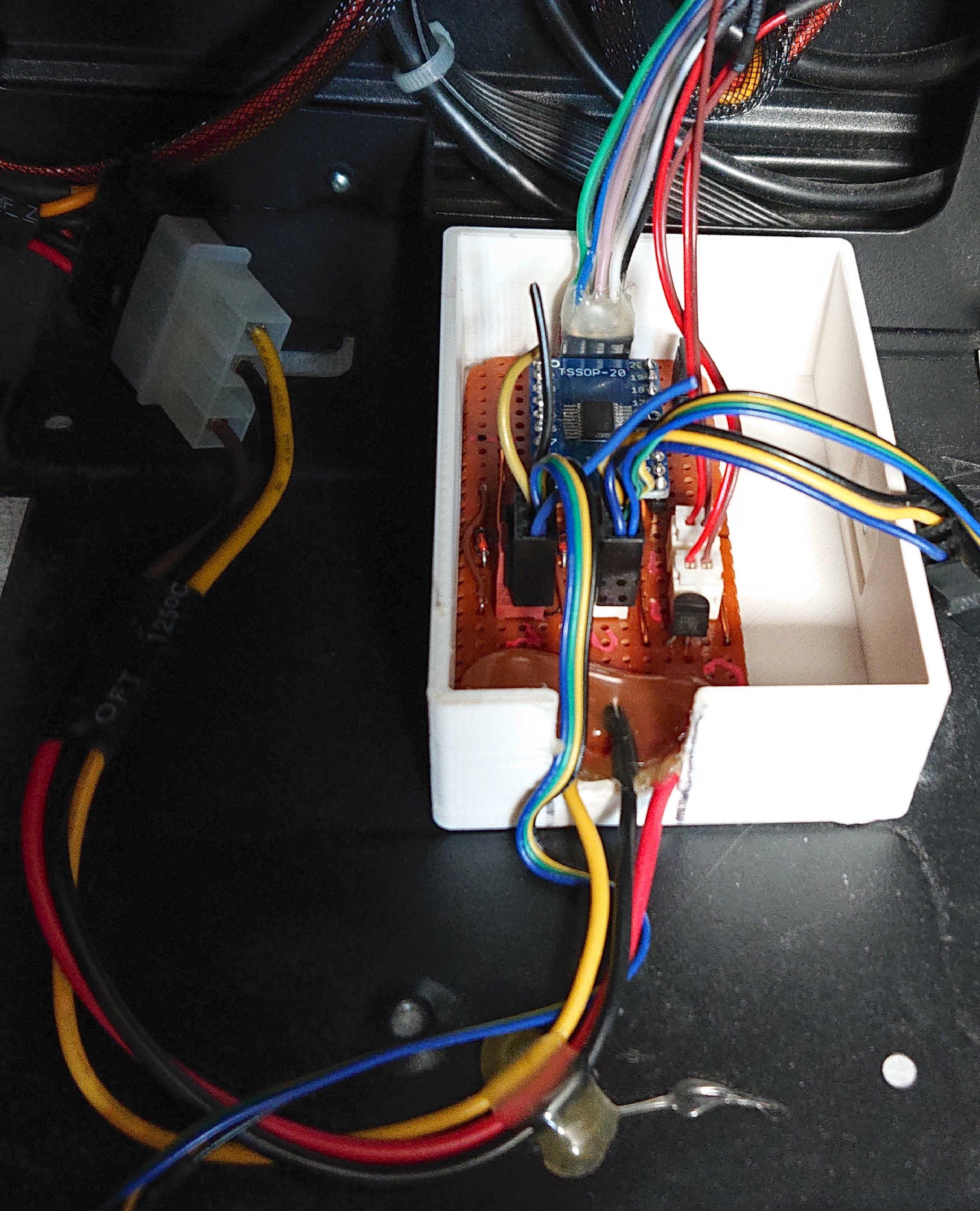 A PCB inside a white plastic enclosure that has been glued into a desktop PC case